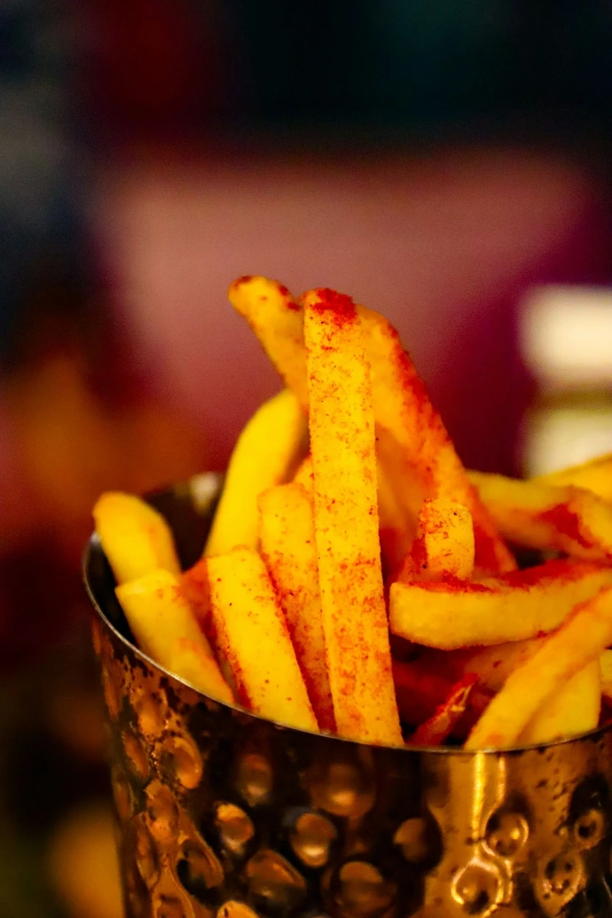 a metal cup filled with french fries on top of a table